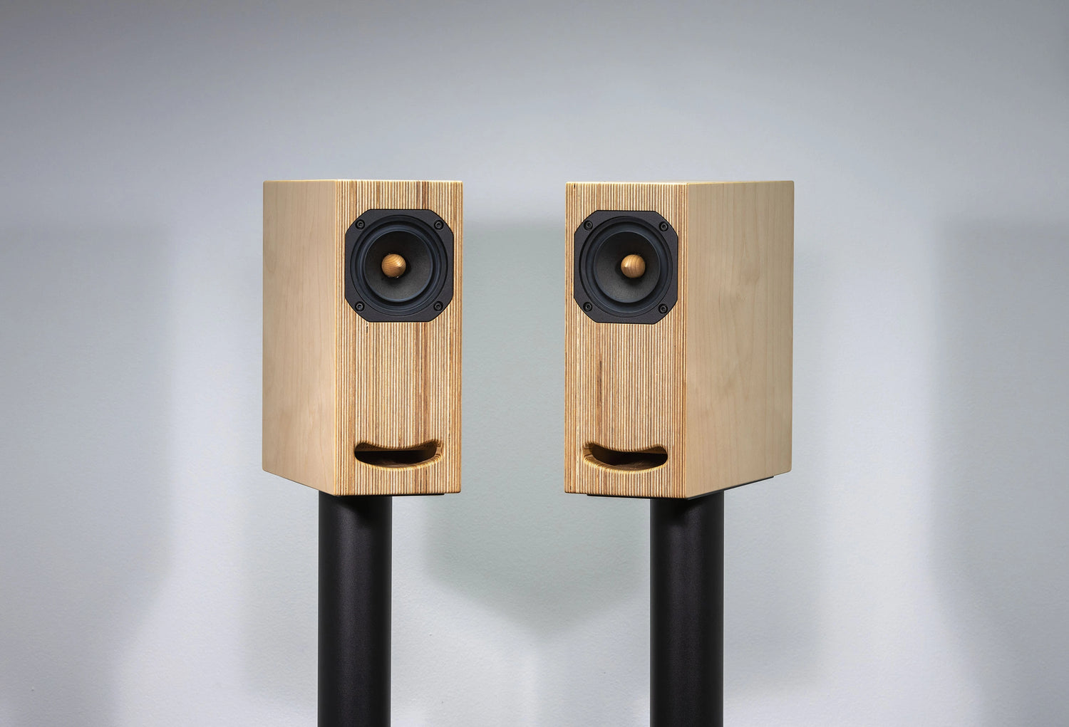 Closer Acoustics OGY bookshelf speakers in natural plywood on black stands, designed for a modern home audio setup with high-end sound