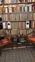 Closer Acoustics Ogy white speakers placed on a bookshelf surrounded by books and vinyl records, blending modern audio design with a cozy, stylish setting.