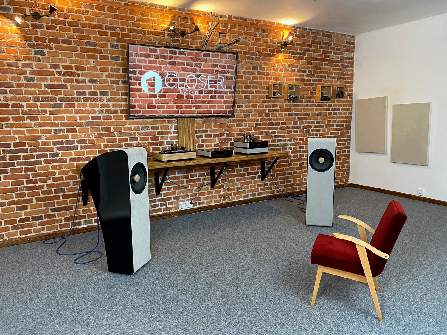 Closer Acoustics Vigo in proper position in listening room for excellent sound with red chair in front