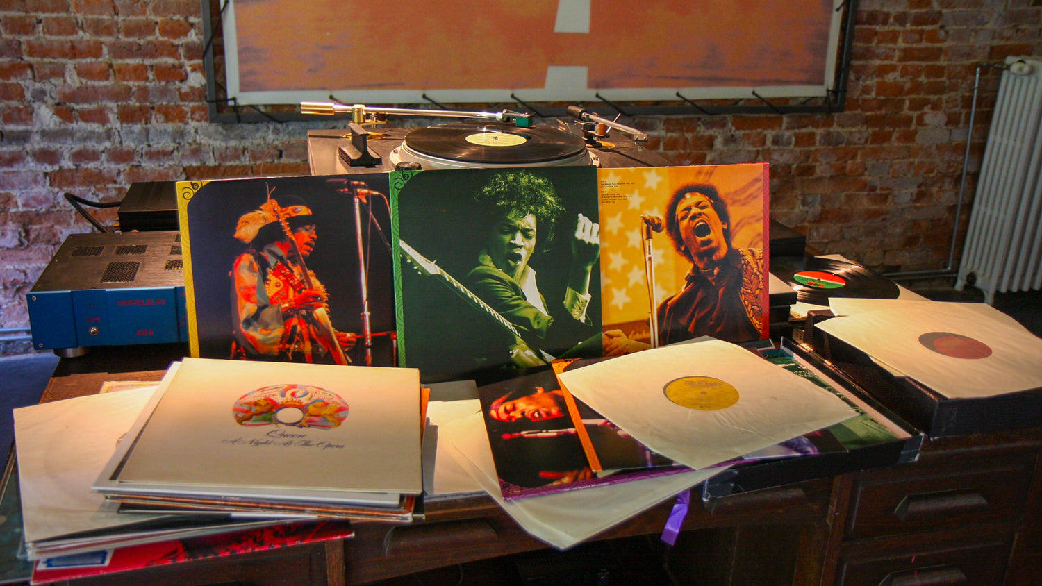 Vinyl records of Jimi Hendrix and Queen on a wooden table, showcasing iconic album covers and classic music heritage.