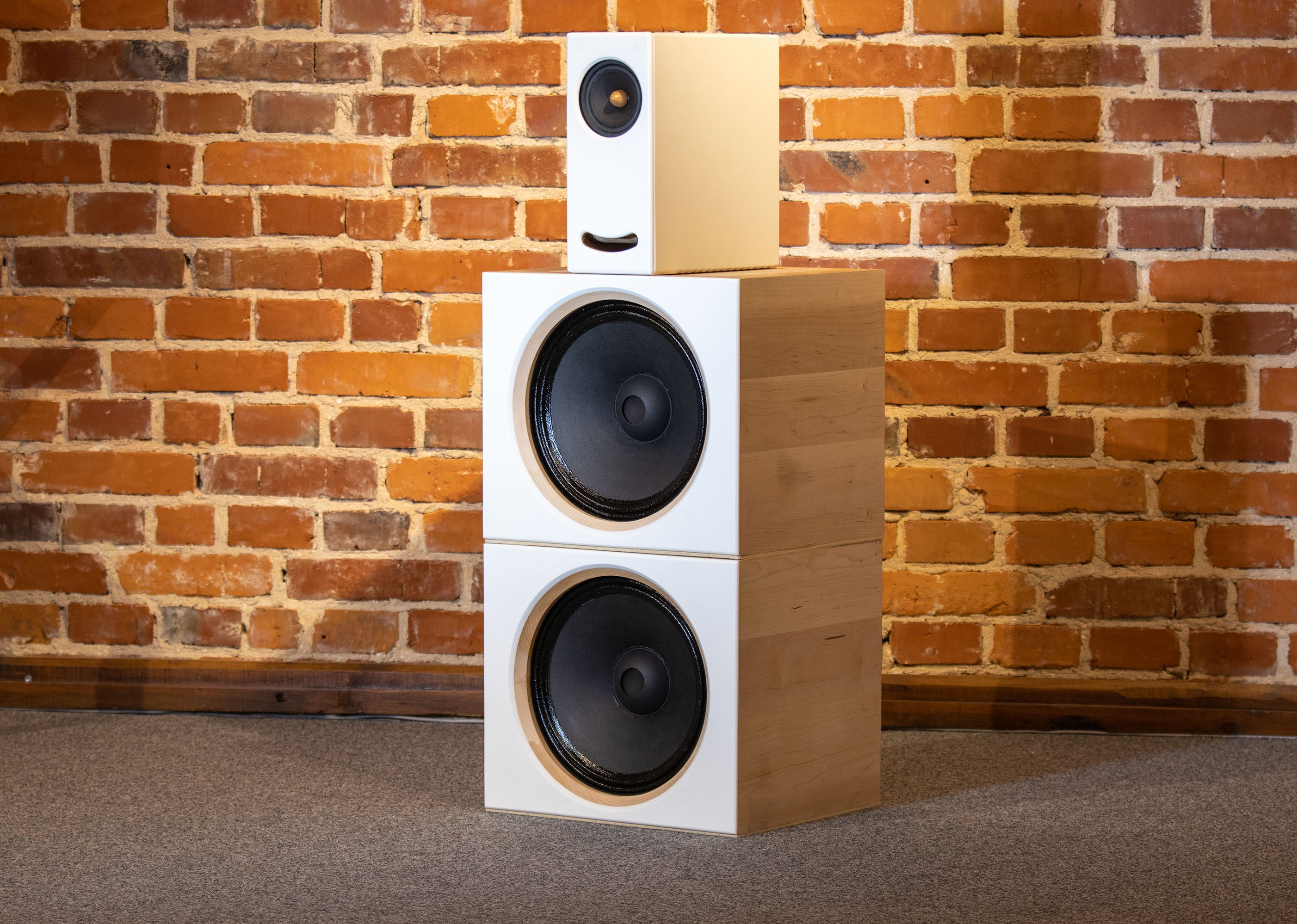 Closer Acoustics OGY plus 2 x BOBs set with white fronts and maple veneered sides, elegantly displayed against a textured brick wall for a sophisticated look
